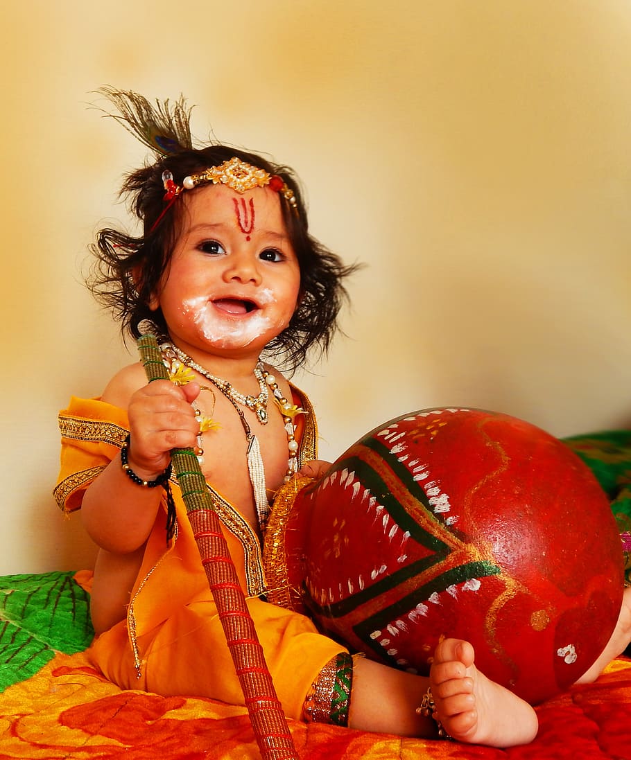 baby holding red and brown staff, lord krishna, hindu, one person