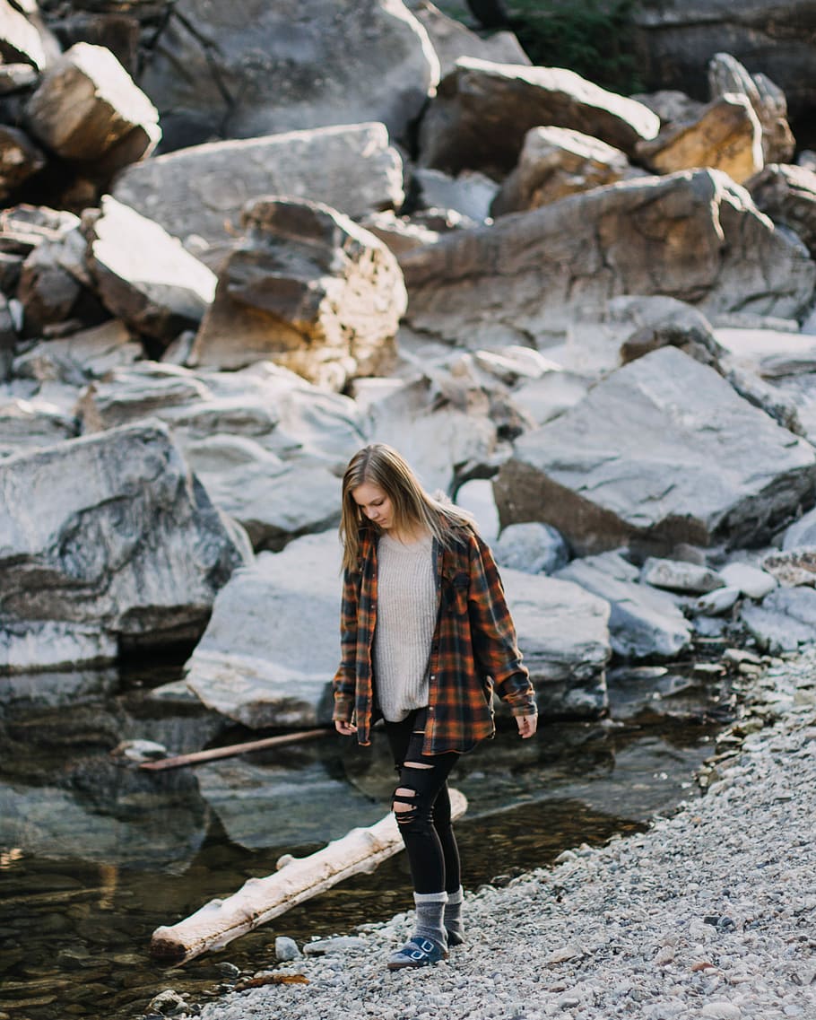 woman walking beside body of water, woman standing near body of water with pile of rocks, HD wallpaper