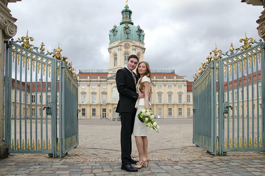 man and woman taking picture standing in front of cathedral during daytime HD wallpaper