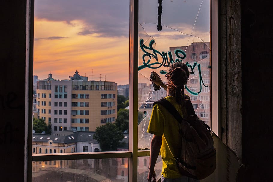woman doing graffiti art in window glass, woman holding spray bottle looking at broken mirror HD wallpaper