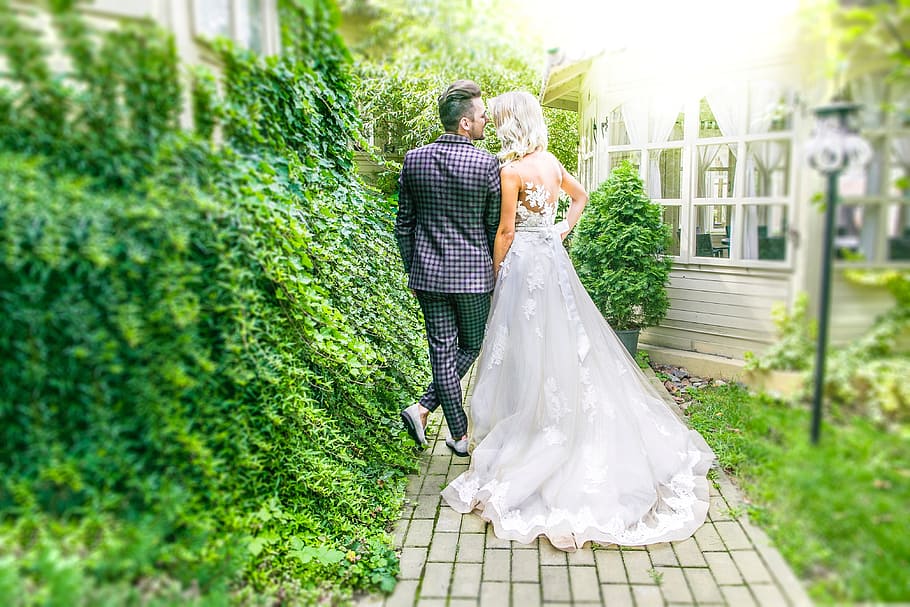 man and woman wearing wedding attire walking on pathway during daytime HD wallpaper