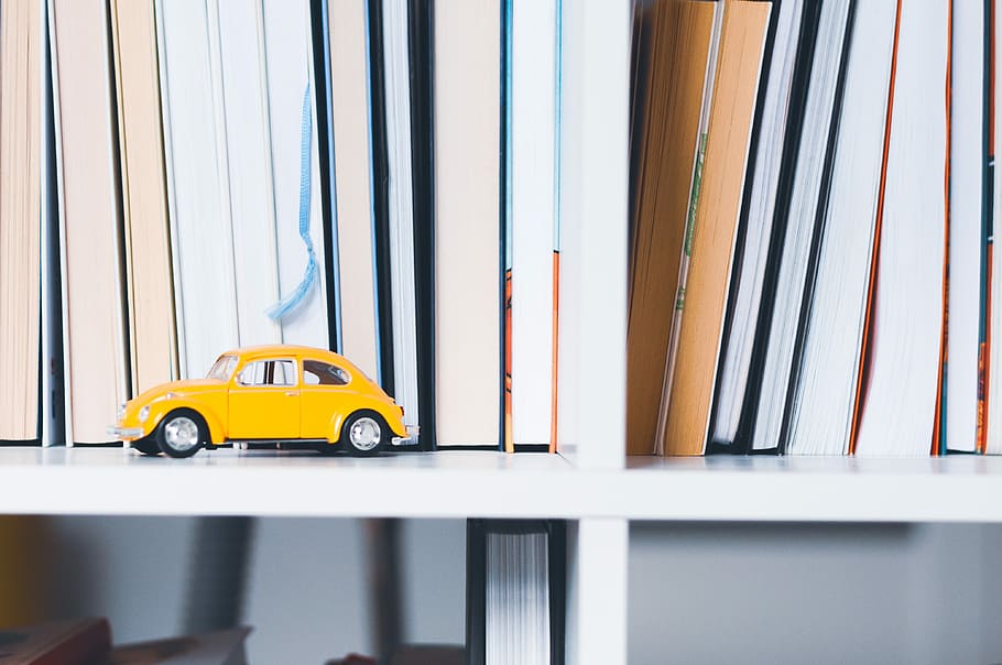 yellow Volkswagen beetle toy on wooden shelf, yellow Volkswagen Beetle scale model near book lot HD wallpaper