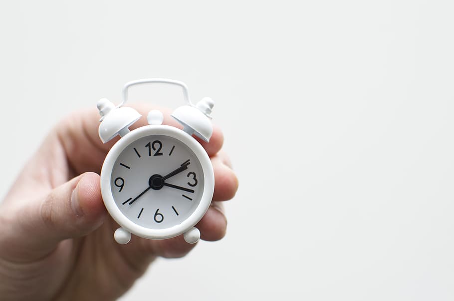 person holding white mini bell alarmclock, person holding mini double bell alarm clock at 2:17 HD wallpaper