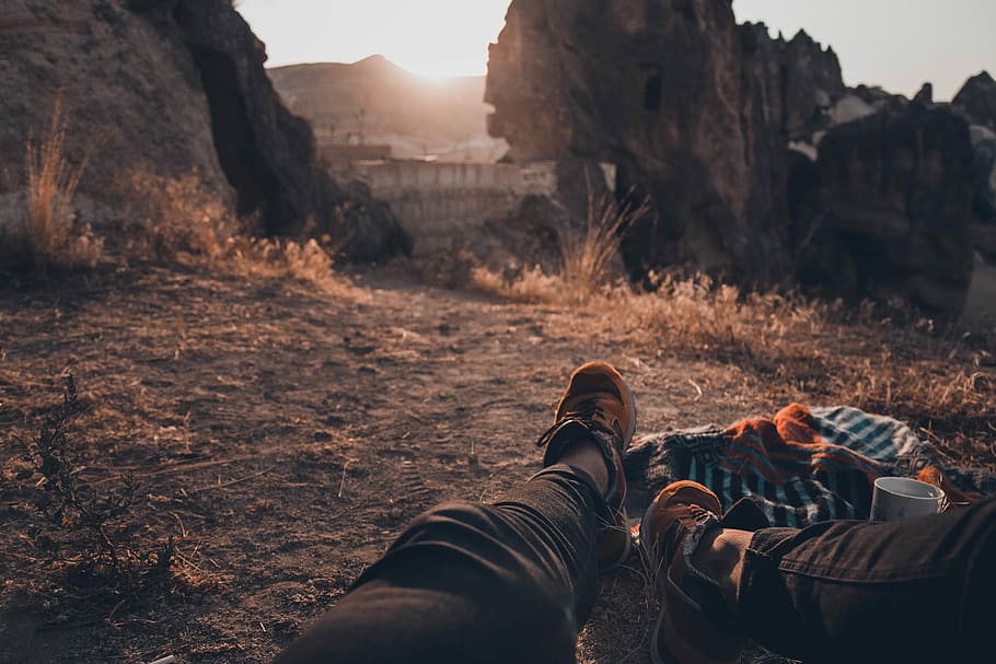 man in black pants lying down on ground, person sitting on ground near cliff HD wallpaper