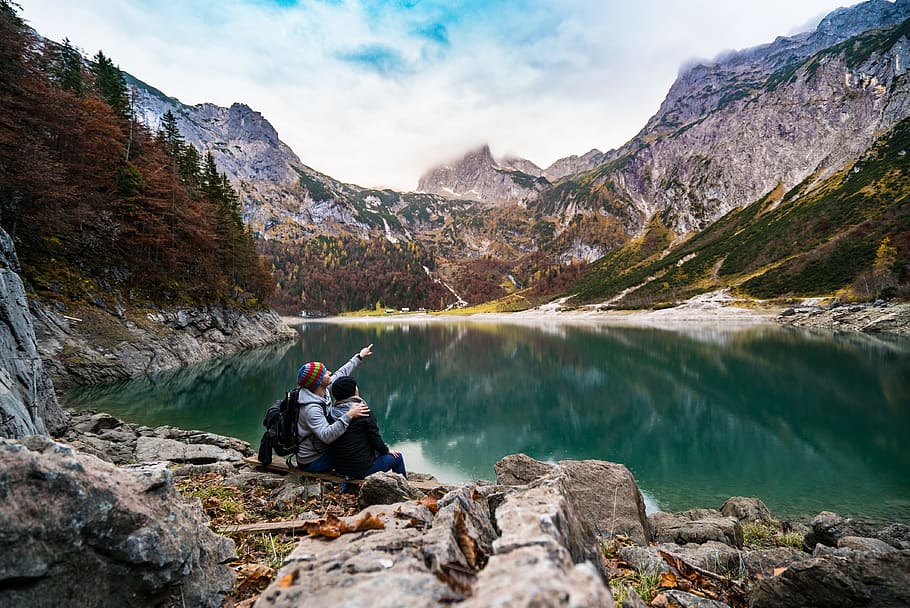 couple sitting on rock near body of water, action, adventure HD wallpaper