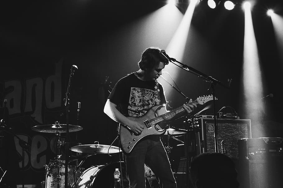 greyscale photo of man playing electric guitar on stage, grayscale photo of man playing electric guitar