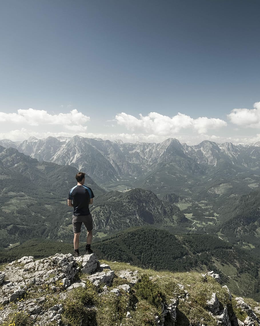 man standing on cliff while staring at the mountain, man standing on mountain range HD wallpaper
