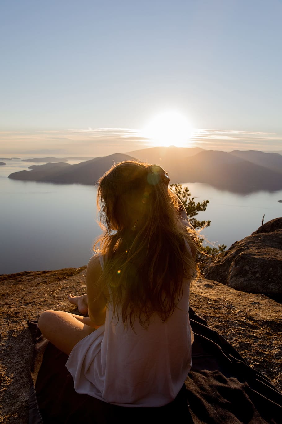 woman sitting on black textile on mountain near lake during daytime HD wallpaper