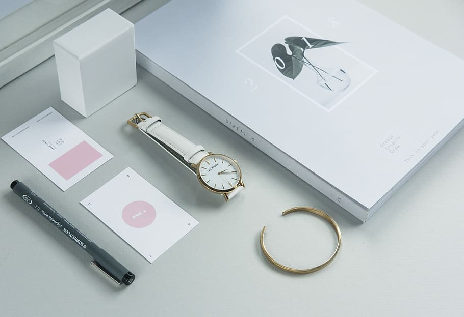 round gold-colored analog watch with white band, round gold-colored and white analog watch with white leather band beside black pen and white labeled box, HD wallpaper