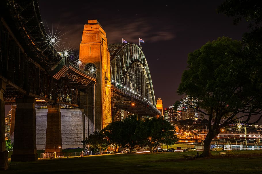 concrete footbridge photography, bridge near trees and city buildings during nighttime HD wallpaper