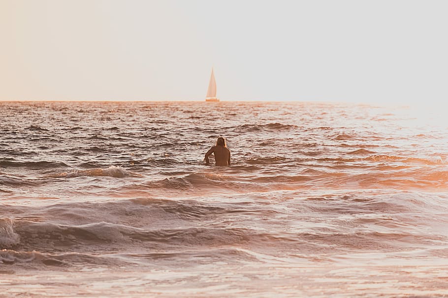 person riding surfboard during golden hour, man in body of water HD wallpaper