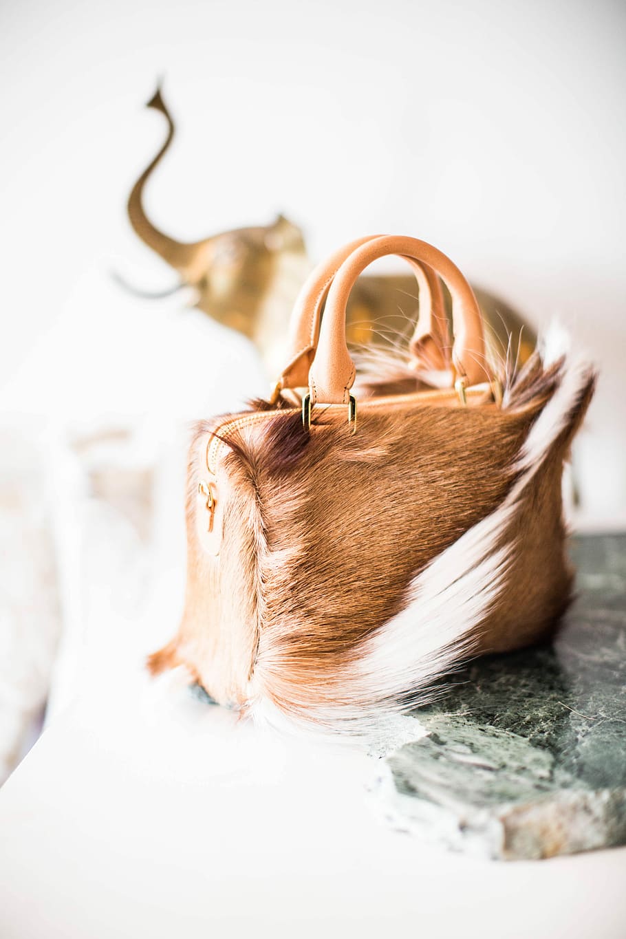 selective focus photography of brown and white leather handbag, brown fur handbag on grey marble-top HD wallpaper