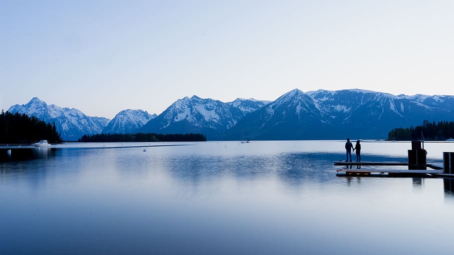 landscape photography of 2 person standing on dock during daytime