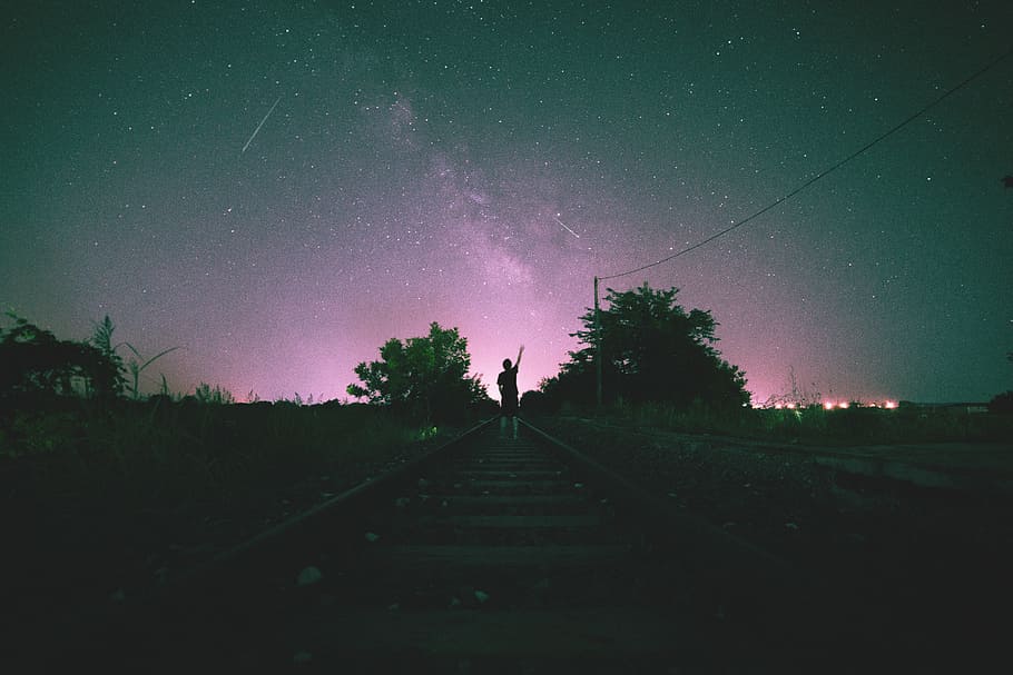 person in middle on train track during night time, silhouette of man standing on train tracks during nighttime HD wallpaper