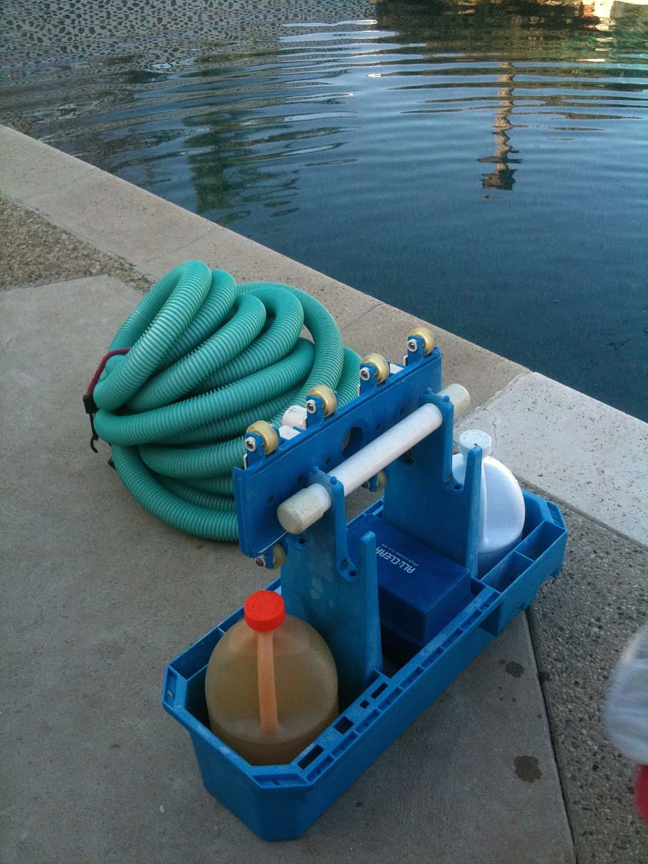 green hose beside blue rack near pool, pool cleaning, pool service