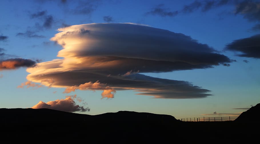 silhouette of hills and fence during golden hour, lenticular cloud