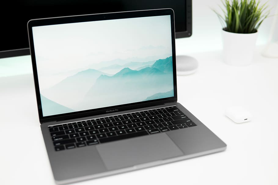 MacBook Pro on white top, turned-on MacBook Pro with cloudy mountain wallpaper HD wallpaper