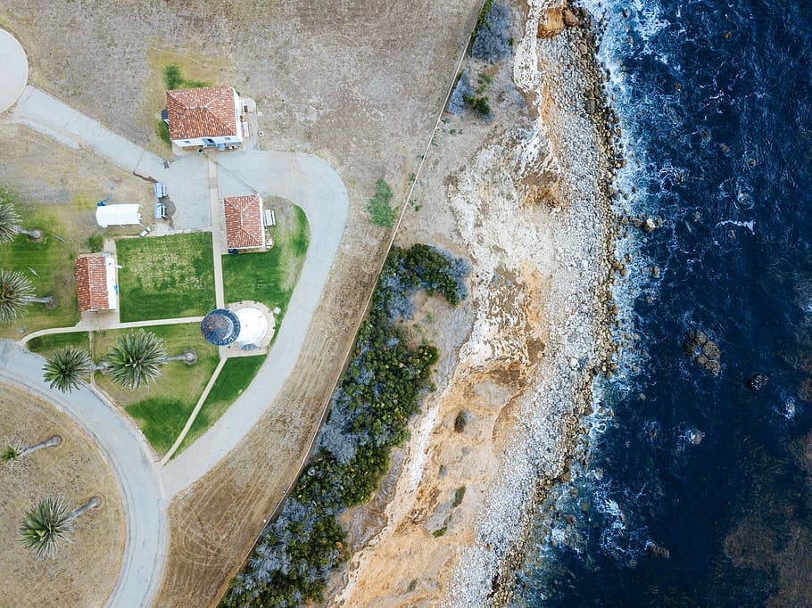 bird's-eye view photography of lighthouse nearby sea, aerial view of building on seashore near body of water