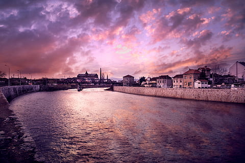 Sunset over the old part of city Niš, body of water between buildings in front of bridge HD wallpaper