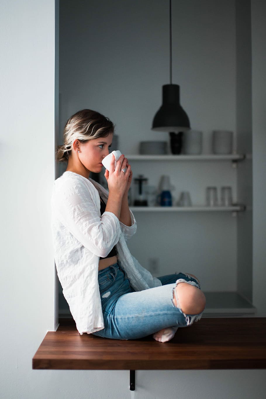 woman sipping cup white sitting on window, woman sitting on brown wooden platform sipping on white ceramic cup HD wallpaper