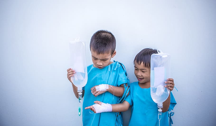 two patient boys holding dextrose bags, children, blue, lab, gown