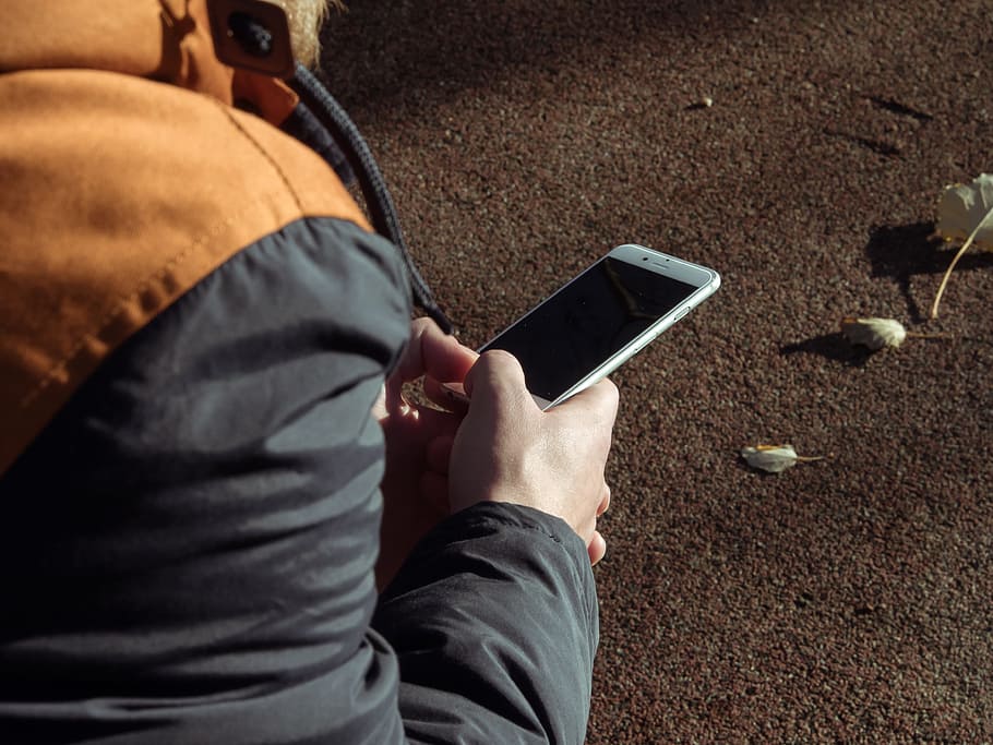 person in black jacket using white smartphone outdoors, apple HD wallpaper