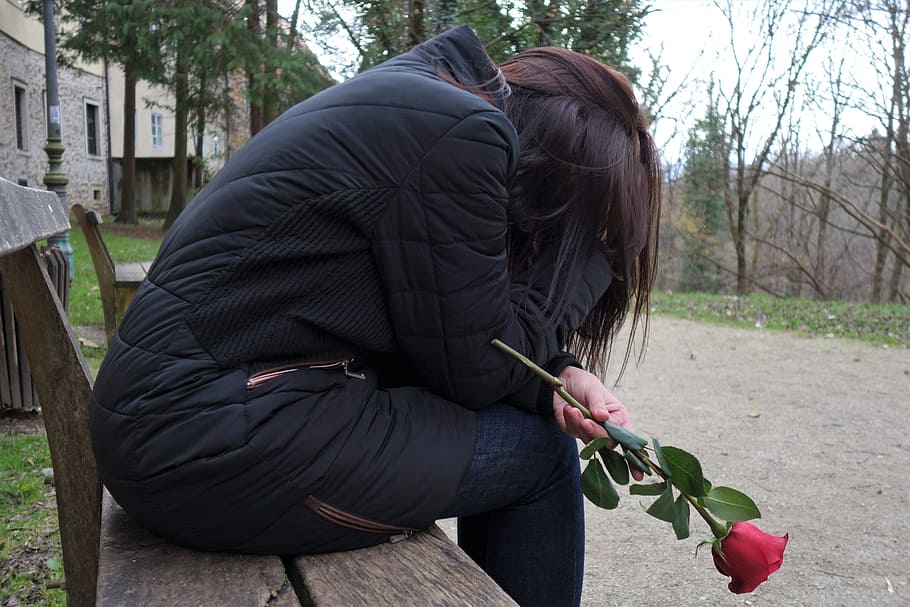 woman sitting on bench chair holding red rose, sad girl, lonely