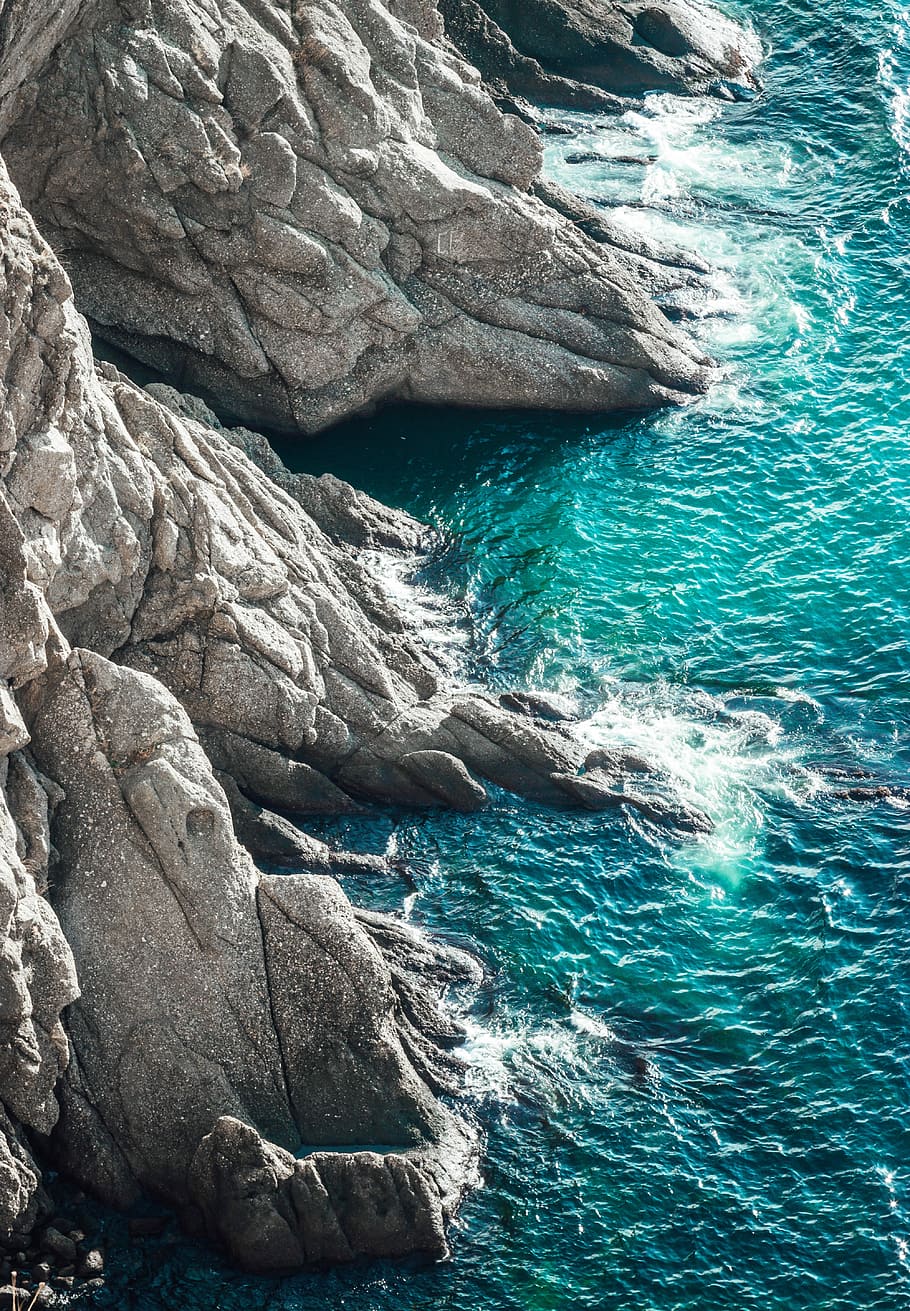 gray cliff near body of water at daytime, aerial photo body of water splashing on rocks HD wallpaper