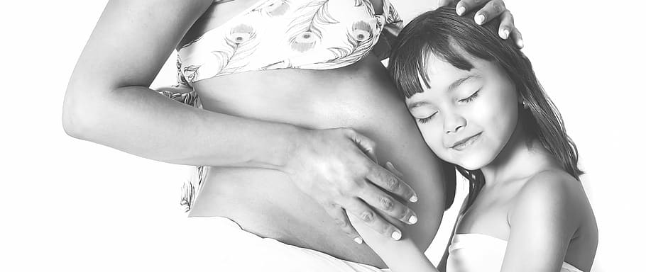girl in white tube dress holding pregnant woman tummy, maternity