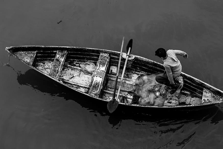 grayscale photography of man standing on boat, grayscale photo of man standing on canoe boat