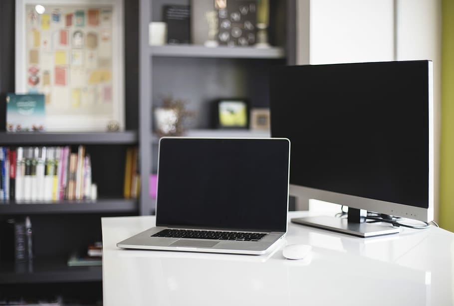 MacBook Pro beside silver monitor on table, MacBook Pro on top of white wooden table HD wallpaper
