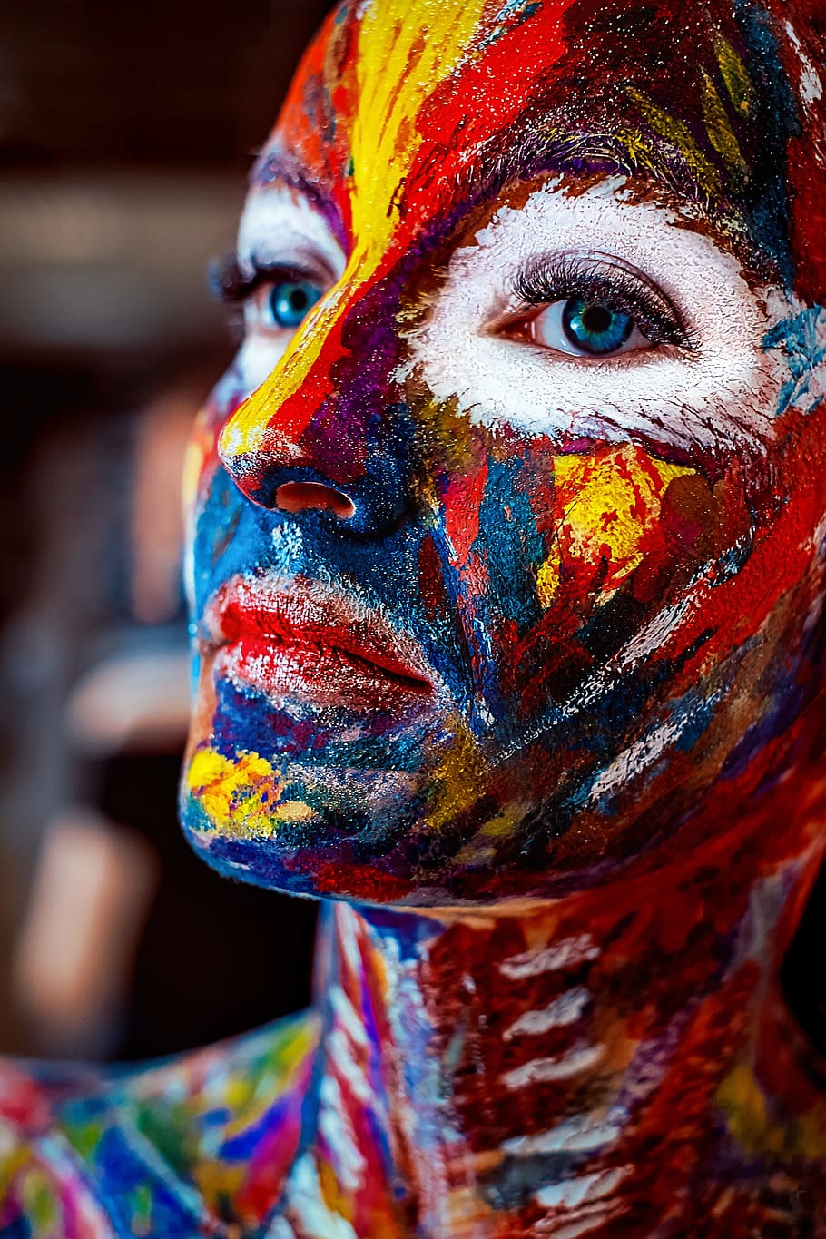 macro photo of multicolored face painted blue-eyed woman, rainbow