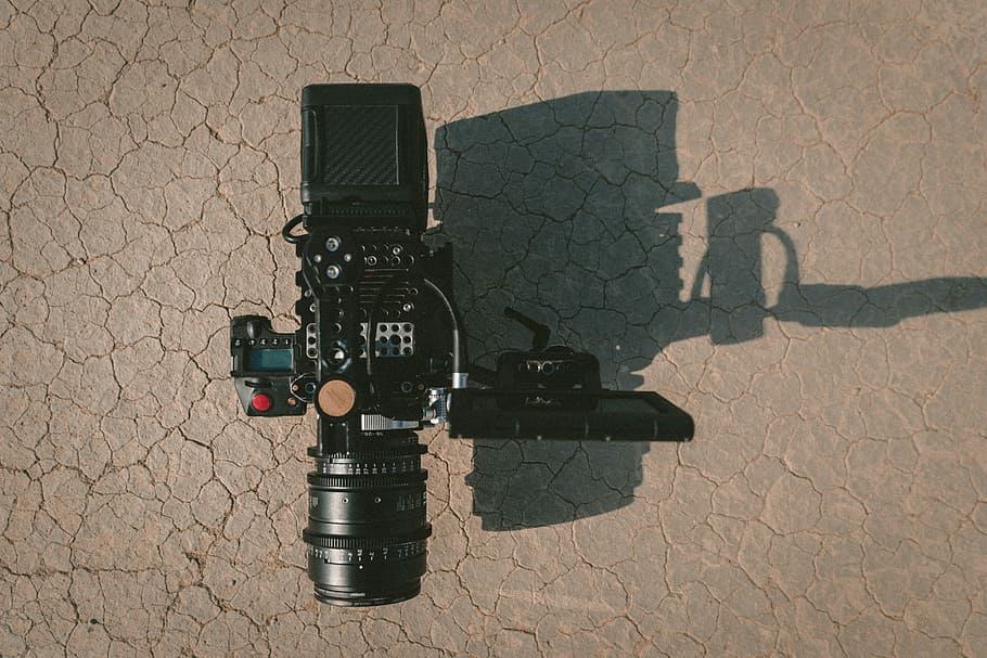 black DSLR camera on brown dirt, black camcorder on gray surface HD wallpaper