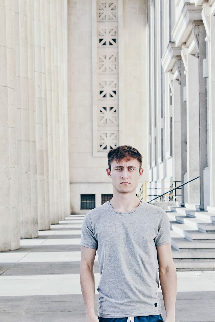 man in gray shirt, man standing inside white concrete building during daytime HD wallpaper