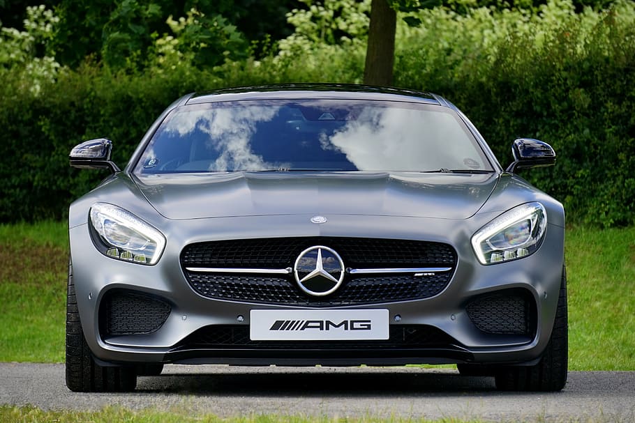 gray Mercedes-Benz AMG parked on concrete pavement near green bush