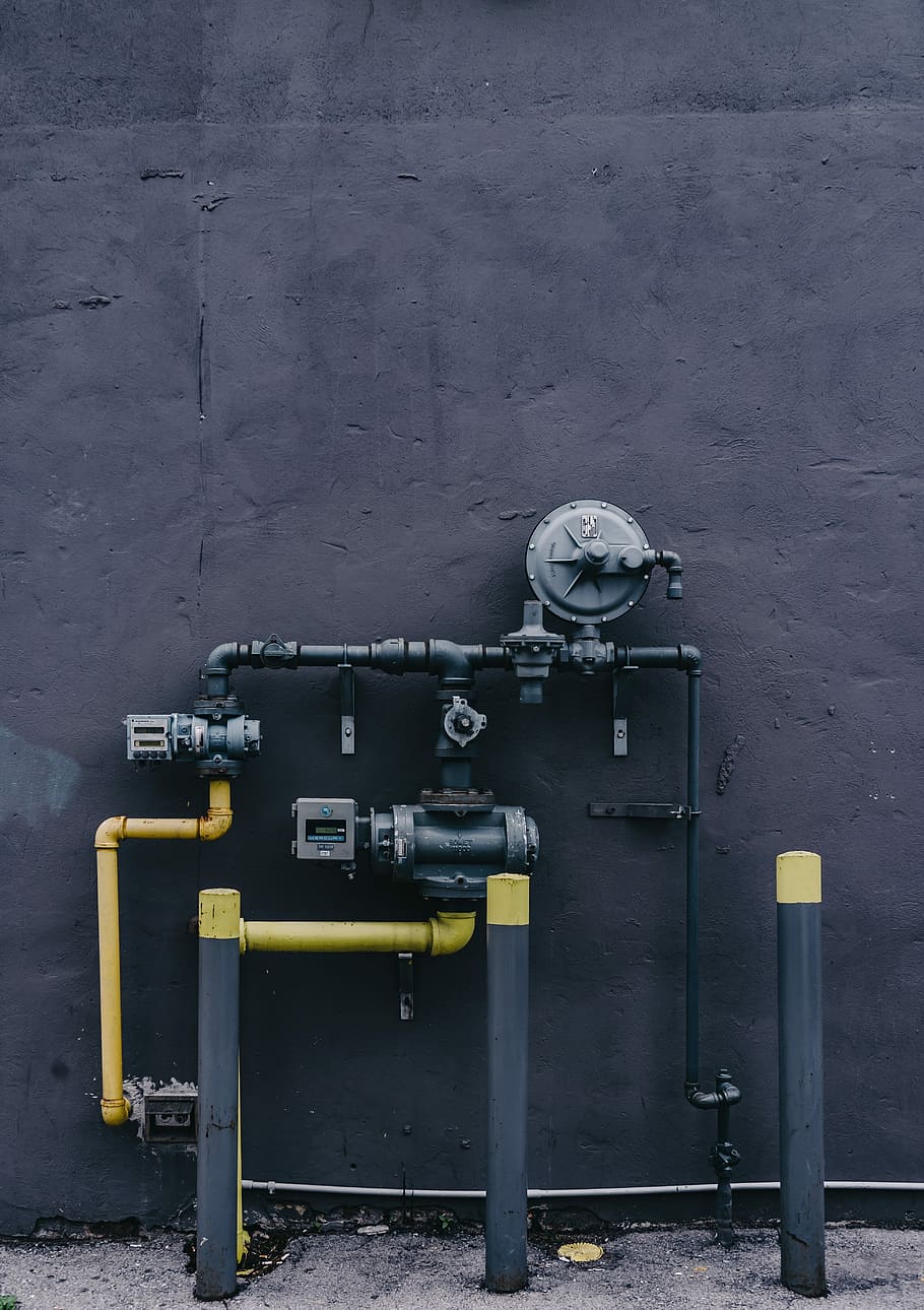 black and yellow water pump system, yellow and black water pipe near concrete wall