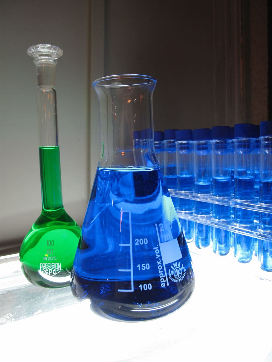 two green and blue liquid filled clear glass containers, lab