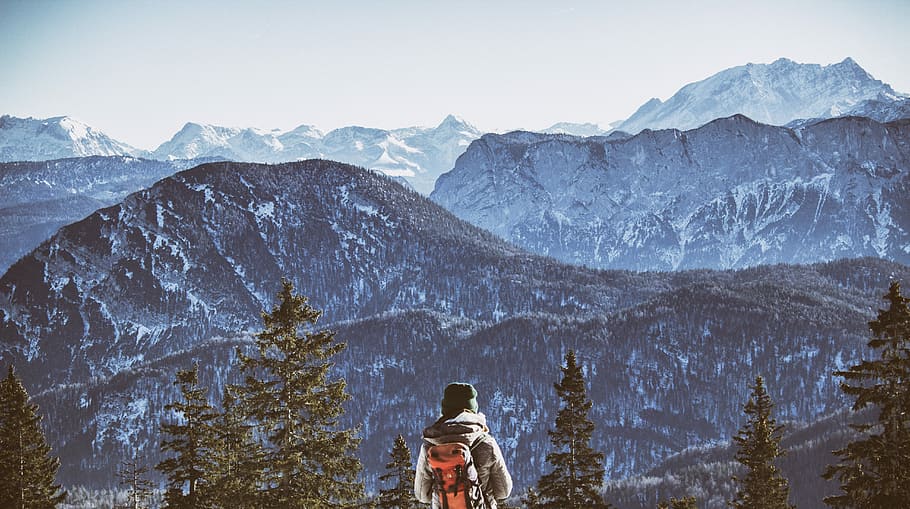 person wearing backpack near mountain during daytim, person with backpack standing on top of mountain with trees during day time HD wallpaper