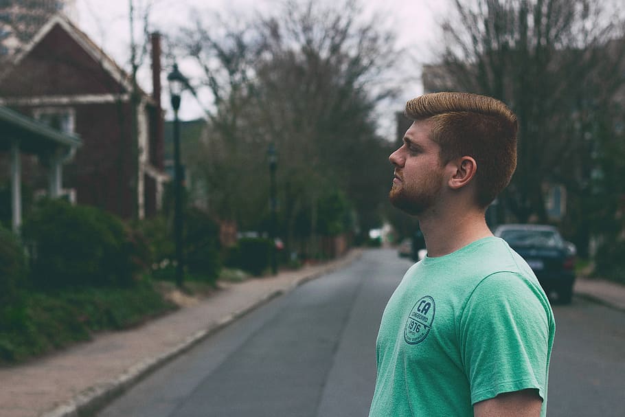 man wearing teal shirt stood in the middle of the street looking on his other side HD wallpaper