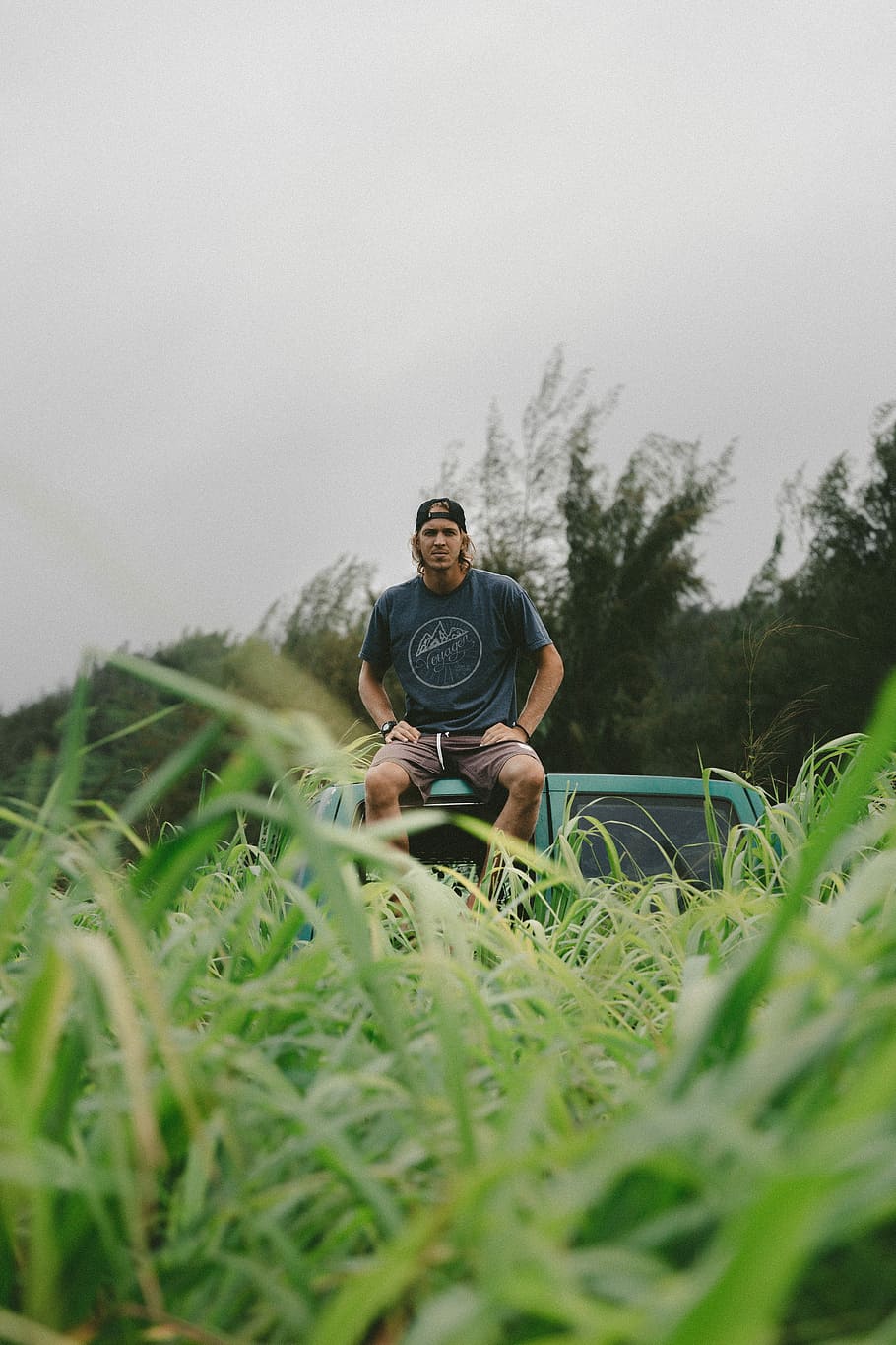 man in black crew-neck t-shirt sitting on green vehicle roof, man sitting on vehicle roof HD wallpaper