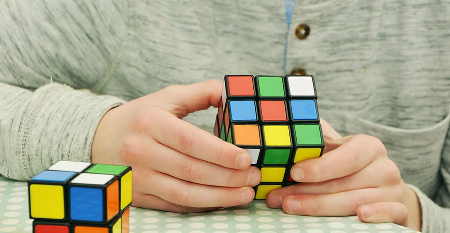 person holding 3 by 3 Rubik's cube, magic cube, patience, tricky