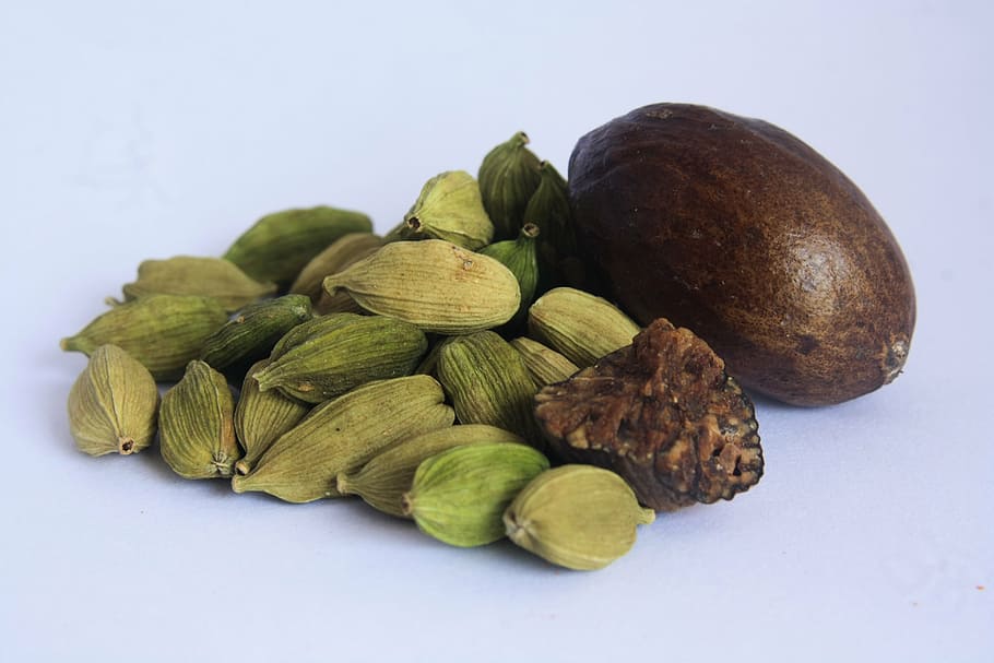 brown and green nuts on white surface, cardamom, spices, food