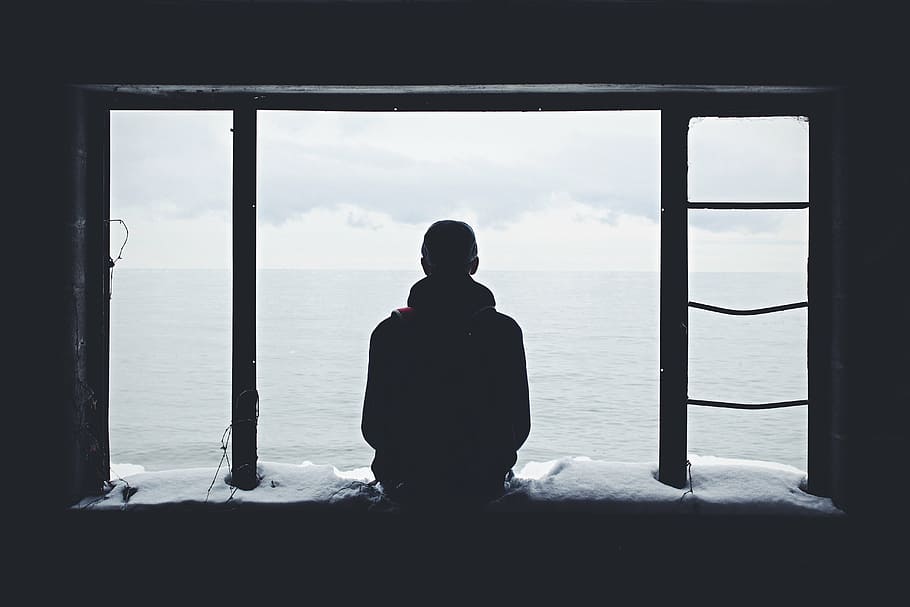 man sitting while looking at the sea, silhouette, person, near