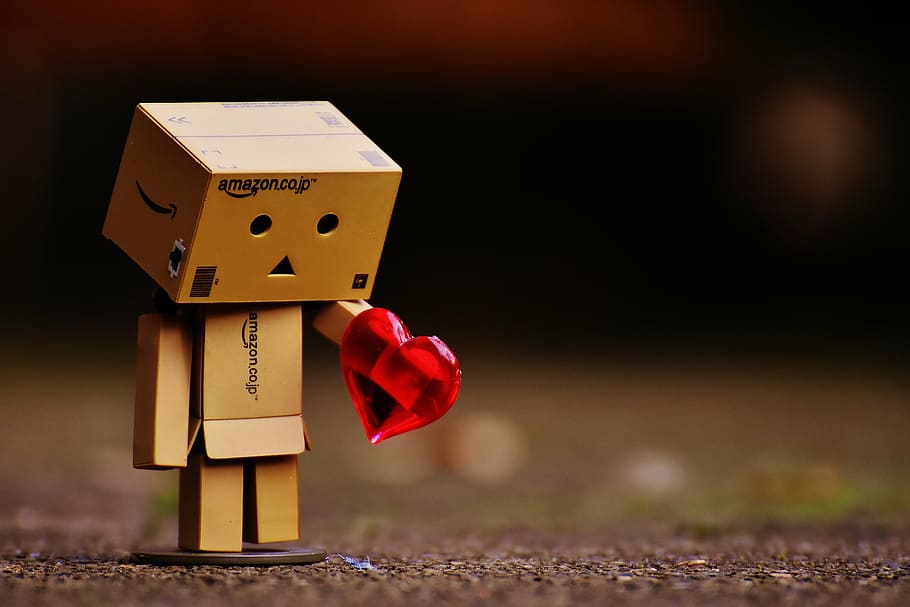 selective focus photography of brown cardboard box person holding heart