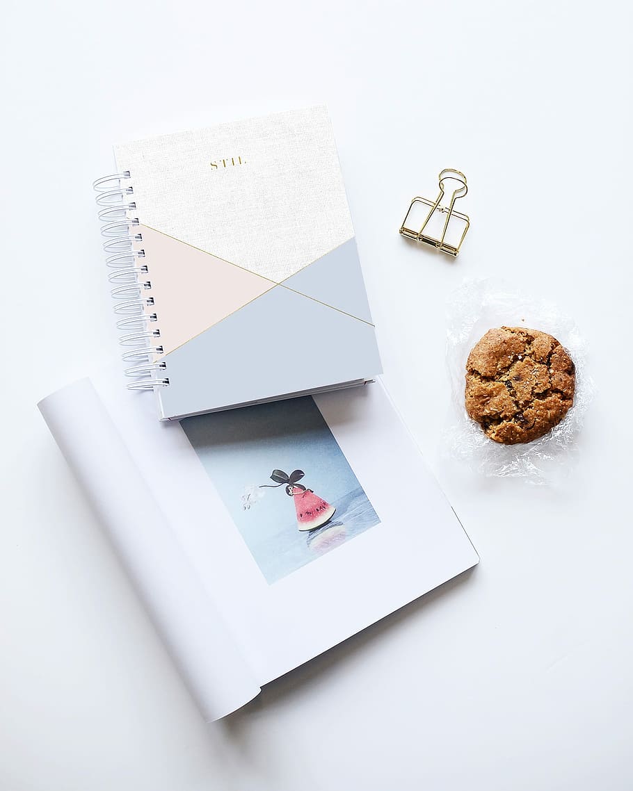 cookie beside two notebooks on white surface, cookie near binder clip and books HD wallpaper