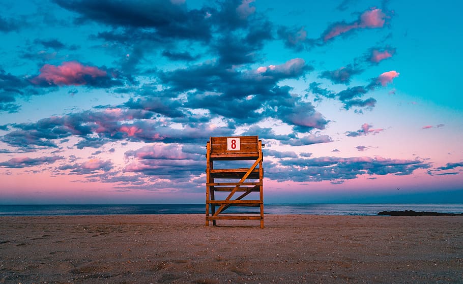 brown wooden stand on shore under gray sky, brown lifeguard chair facing the ocean under the gray clouds HD wallpaper