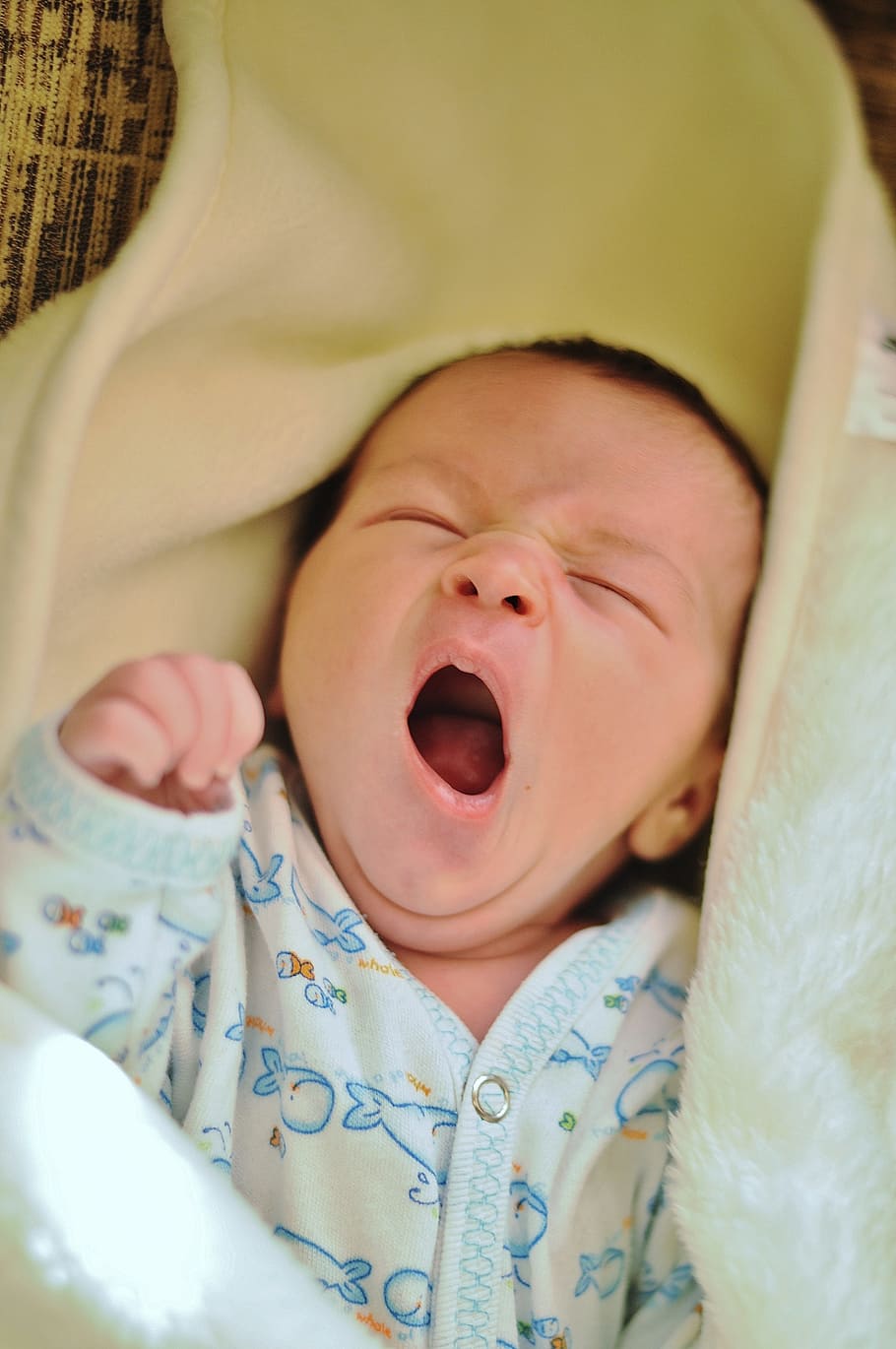 baby wearing onesie yawning with blanket, white, shirt, yellow