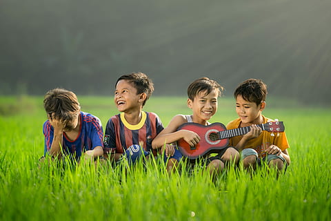 four boys laughing and sitting on grass during daytime, four boys sitting on green grass HD wallpaper