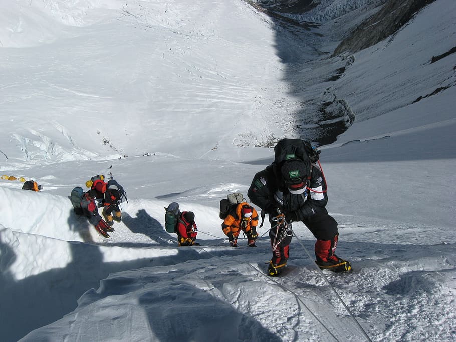 group of people hiking on snow mountain cliff, mount everest