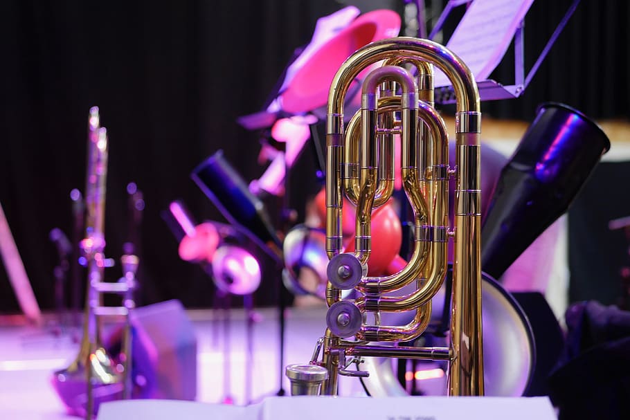 selective focus photo of gold wind instrument, trombone, stage